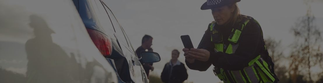Police officer taking a photograph of car damage with a smartphone